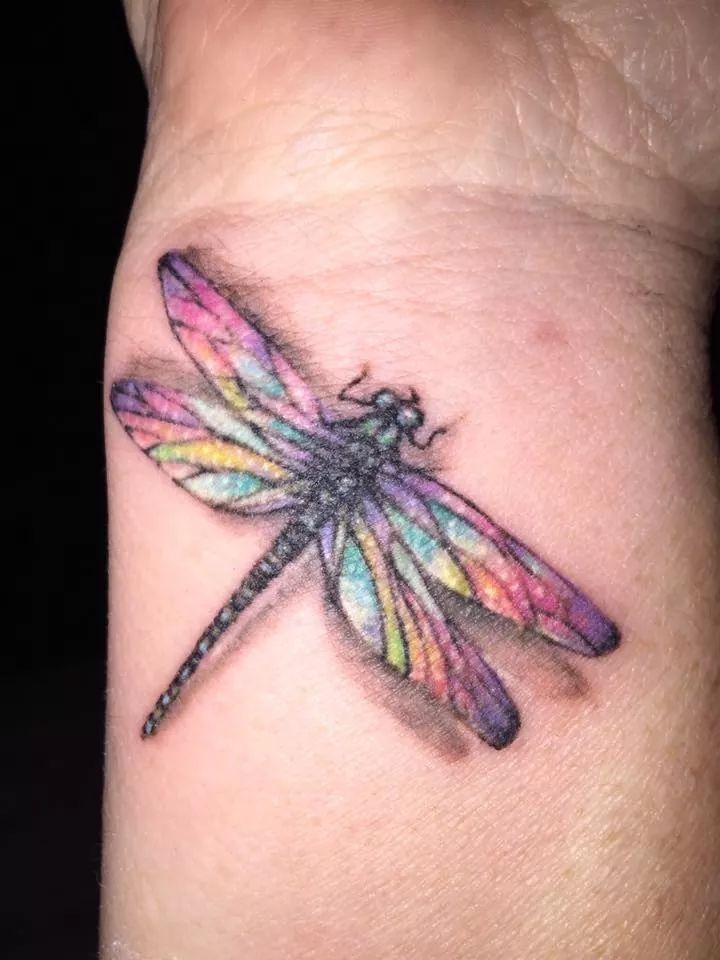 a colorful dragonfly tattoo on the wrist