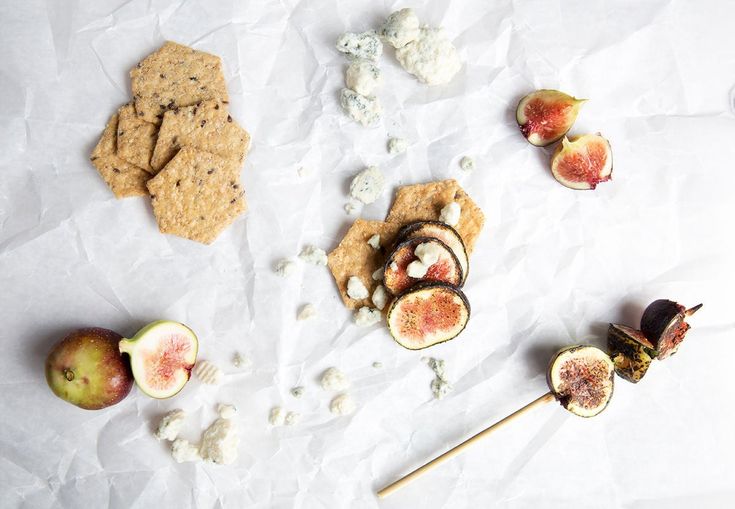 an assortment of snacks including crackers, figs and fruit on a piece of paper