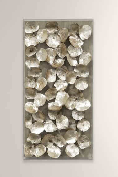 a white wall with some silver rocks on the bottom and one is in front of it