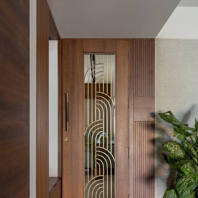 a wooden door with an art deco glass paneled design on it and a potted plant in the foreground