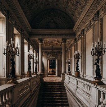 an ornate hallway with chandeliers and marble steps leading up to the second floor