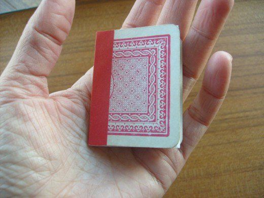 a small red and white playing card held in someone's hand