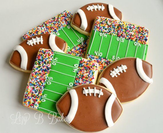 decorated cookies with footballs and sprinkles are arranged on a white surface