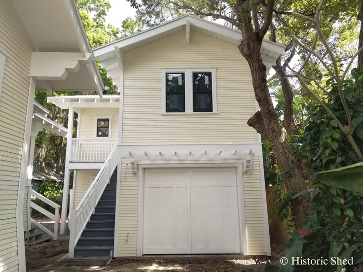 a two story white house with stairs leading up to it