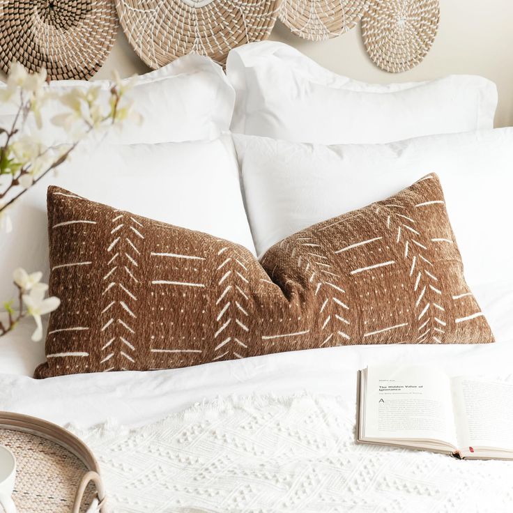 a bed with white linens and pillows on top of it next to an open book