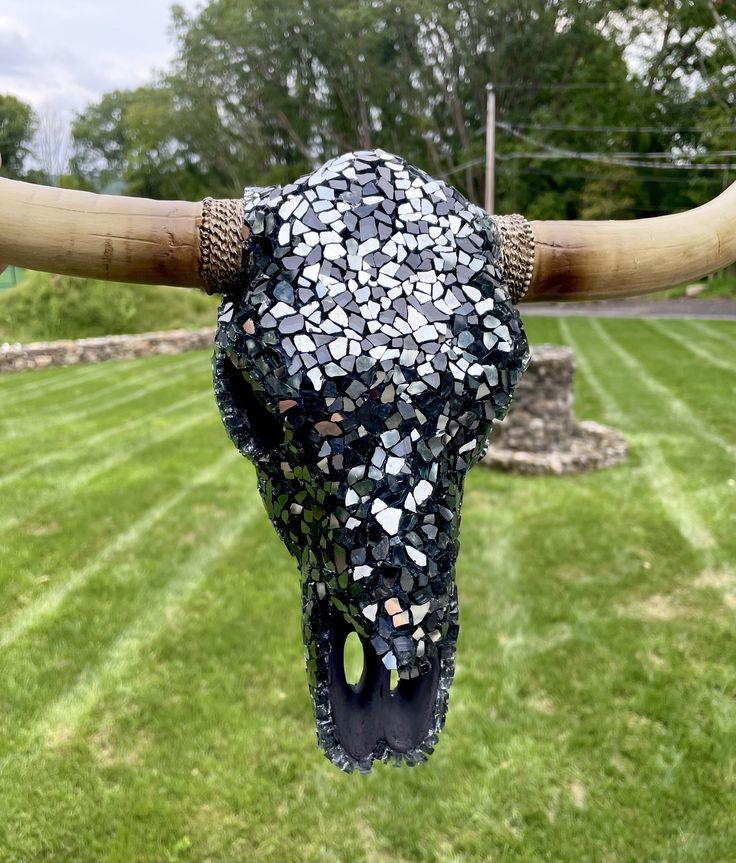 a cow's skull made out of mosaics and wood sticks in the grass