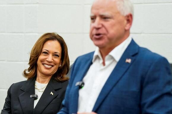 a man and woman standing next to each other in front of a white brick wall