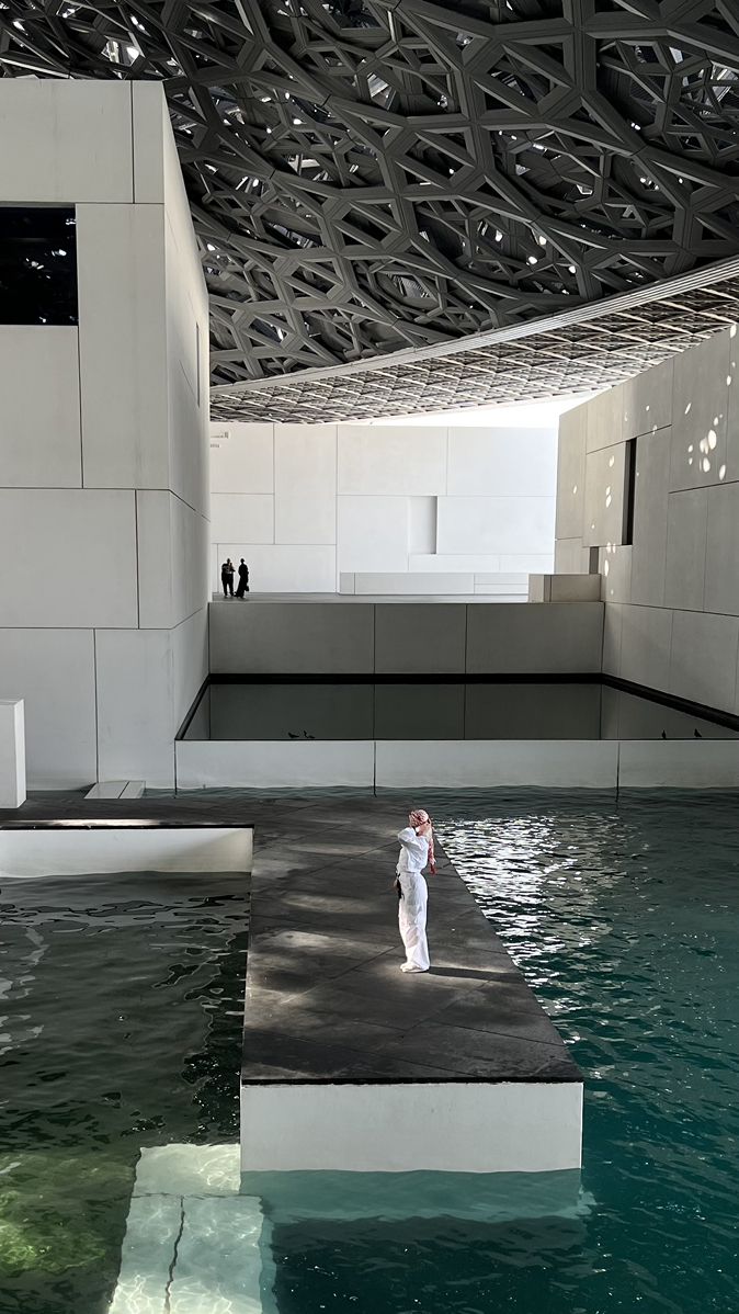 a woman standing on top of a floating platform in the water next to a building