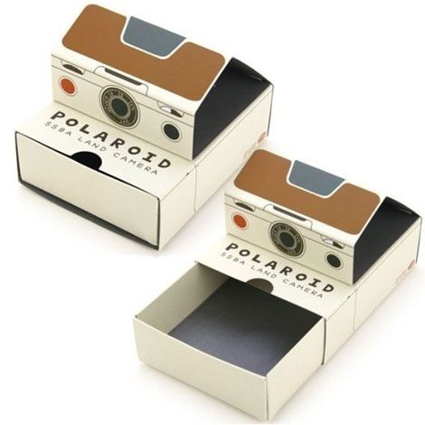 two polaroid cameras sitting in a box on top of each other, one is brown and the other is white