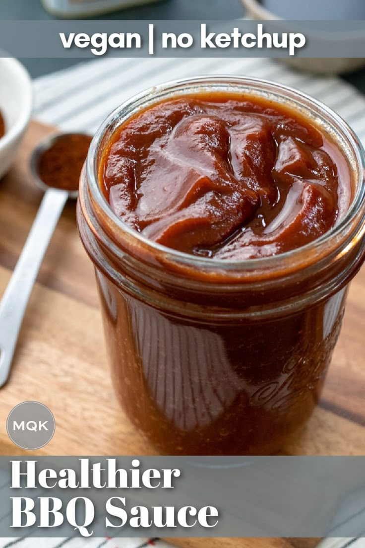 a wooden cutting board topped with a jar of barbecue sauce next to a bowl of bbq sauce