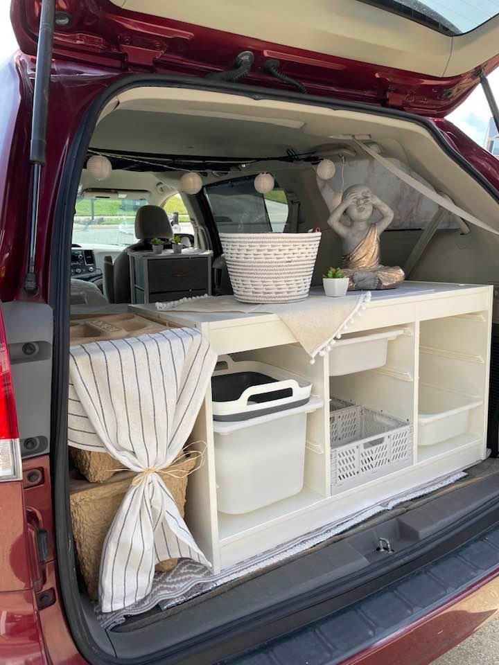 the back end of a red car with baskets and other items in it's trunk