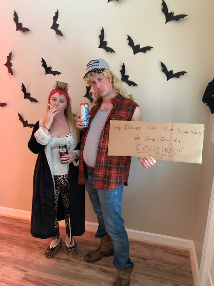 two people standing next to each other with bats on the wall behind them holding signs