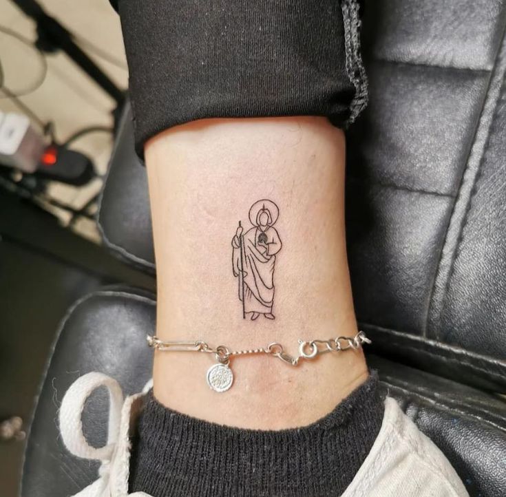 a woman's ankle with a small tattoo on her left leg and a chain around the ankle