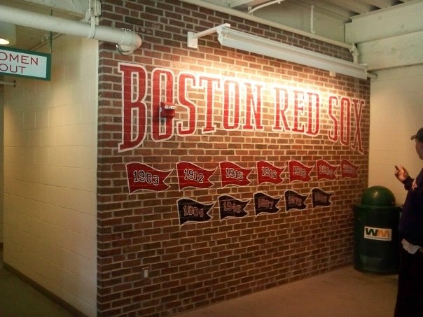 a woman standing in front of a brick wall with boston red sox written on it