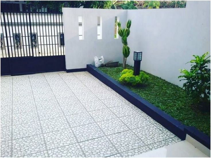 an outdoor courtyard with grass and plants on the ground in front of a white fence