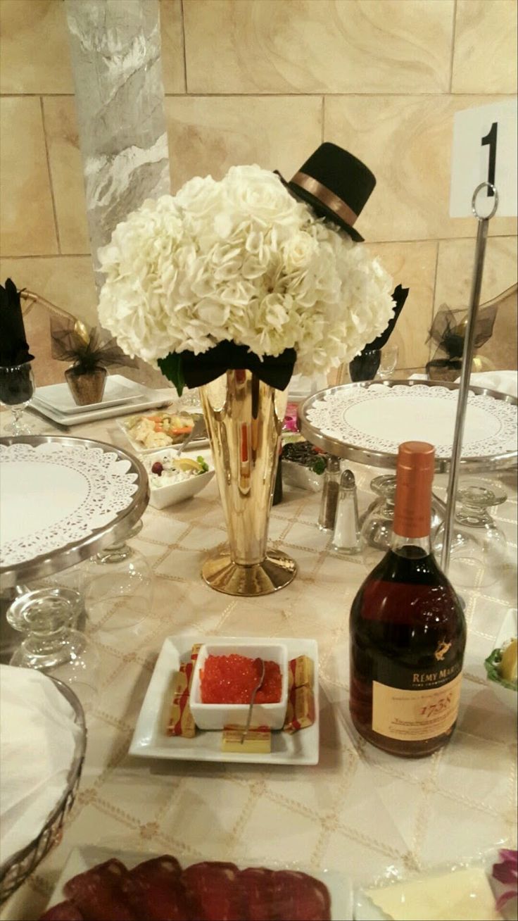 a table topped with plates and vases filled with white flowers next to a bottle of wine