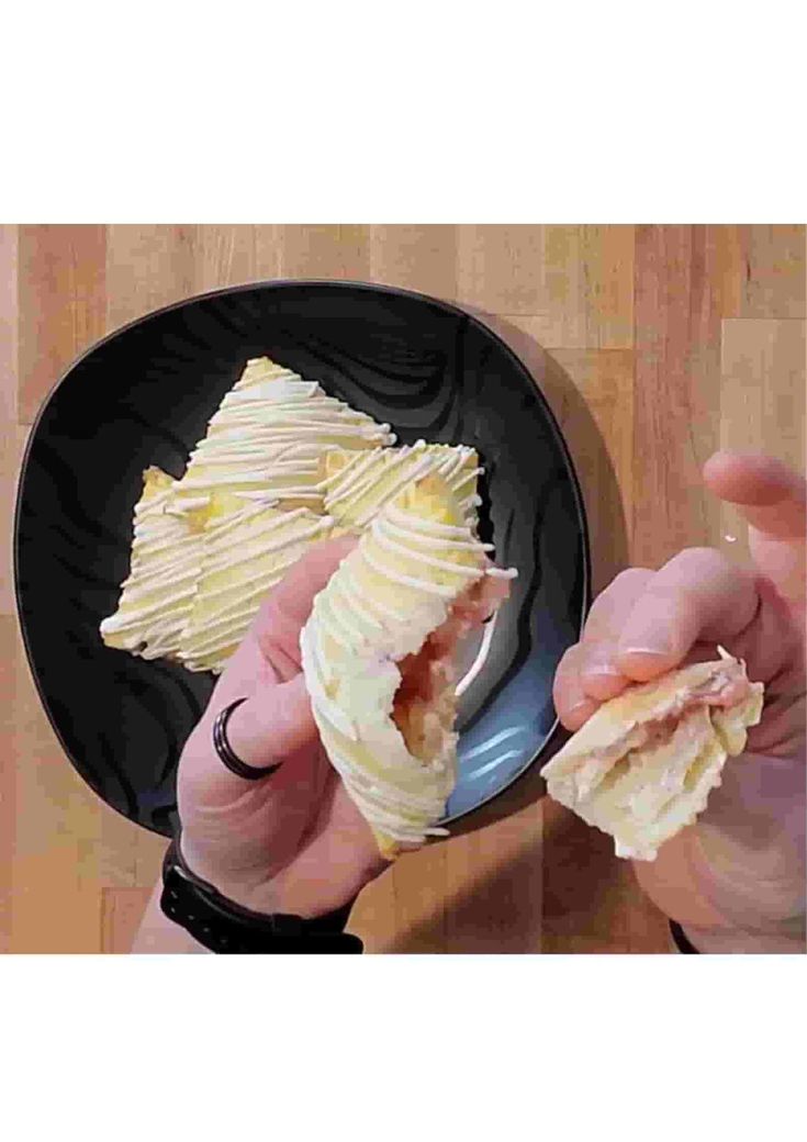 a person is holding some food in their hand and eating it on a black plate