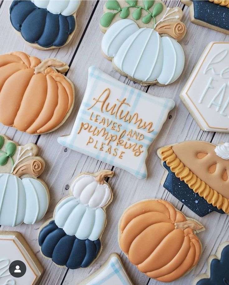 many decorated cookies are arranged on a white wooden surface with the words autumn leaves and pumpkins placed next to them