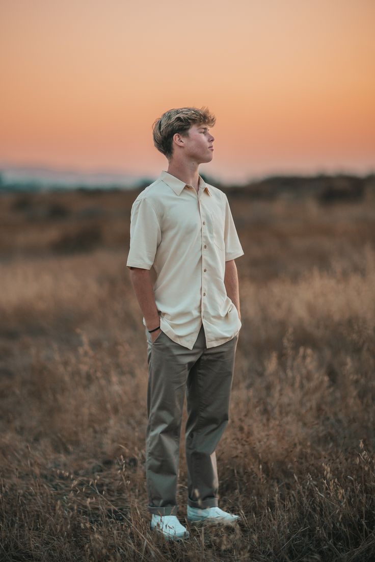 a man standing in a field at sunset