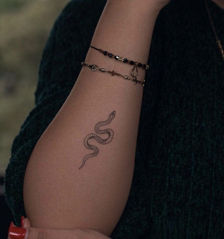 a woman's arm with a snake tattoo on the left side of her arm