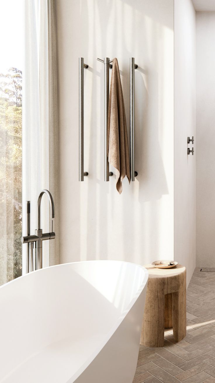 a white bath tub sitting in a bathroom next to a wooden table and two towel racks