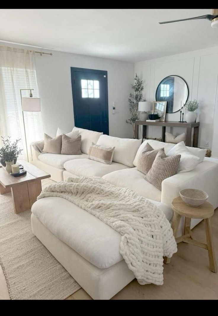 a large white couch sitting in a living room next to a window