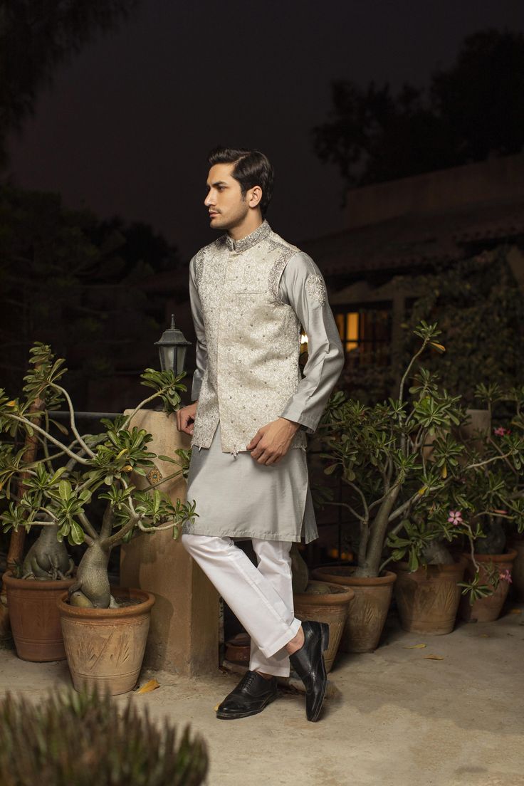 A grey, sophisticated look to pair with the women’s walima suit in our collection. A kurta pajama pairs with a waistcoat for a traditional look. The hand-worked waistcoat features dabka and resham details, featuring shimmering Swarovski stones. The kurta is made of pure karandi while the pajama is made of cotton. 3-Piece Suit, Ready-to-wear, Medium only One-piece only Price is indicative of men’s suit only Click here to see the bride’s suit in our Zar Gul Collection, sold separately. Eid Silver Raw Silk Set, Silver Designer Traditional Wear For Eid, Designer Silver Traditional Wear For Eid, Designer Nehru Jacket With Naqshi For Eid, Eid Nehru Jacket With Dabka On Raw Silk, Designer Naqshi Nehru Jacket For Eid, Unstitched Nehru Jacket With Naqshi For Eid, Sleeveless Traditional Sets For Formal Occasions, Fitted Gray Sets For Eid