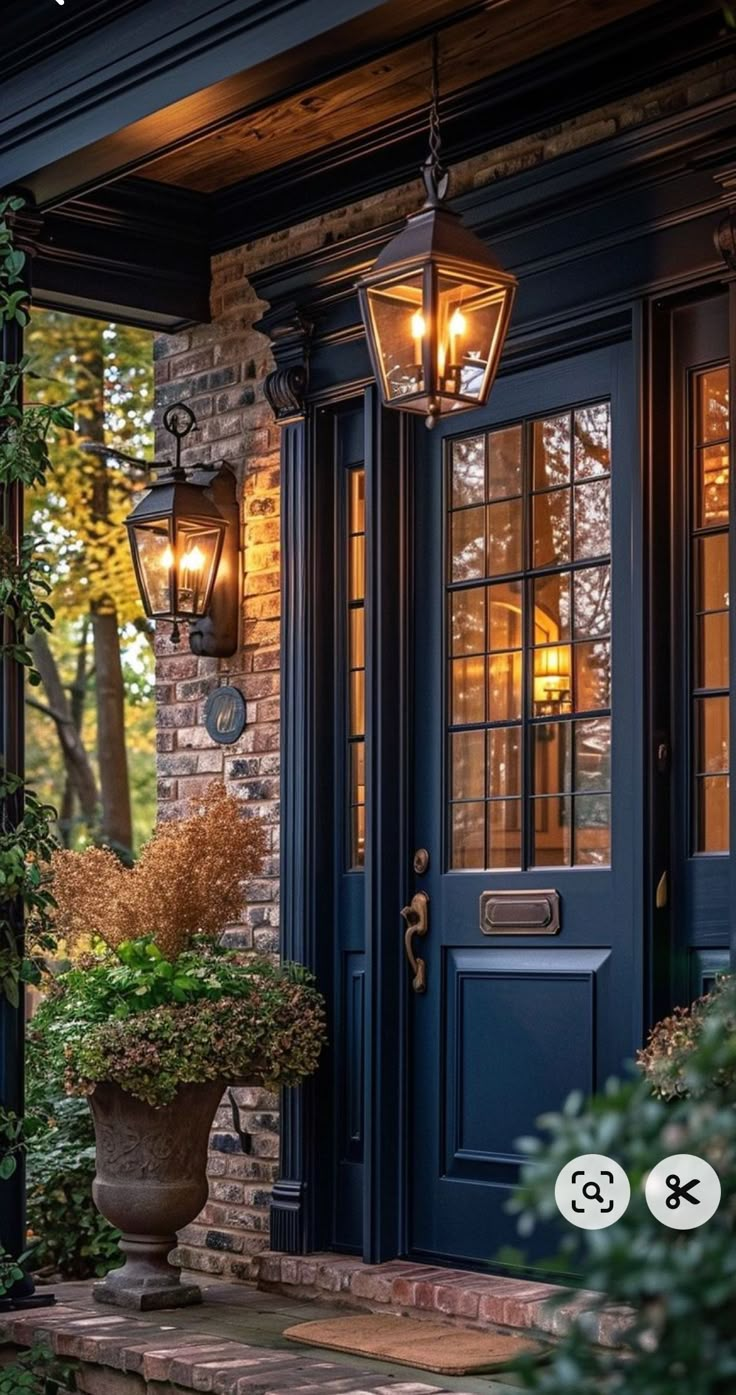 a blue front door with two lights on it and some plants in the foreground