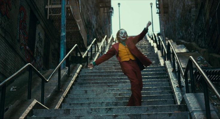 a person in a clown mask walking down some stairs with their arms out to the side