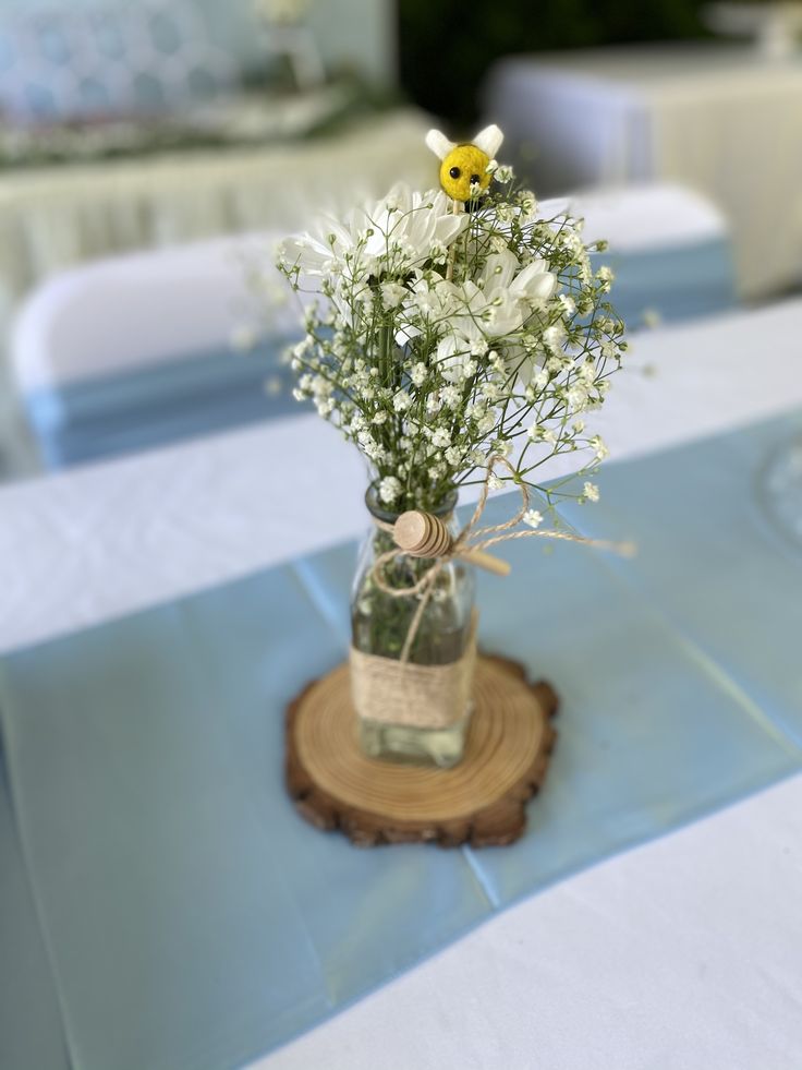 a vase filled with white flowers sitting on top of a blue table cloth covered table