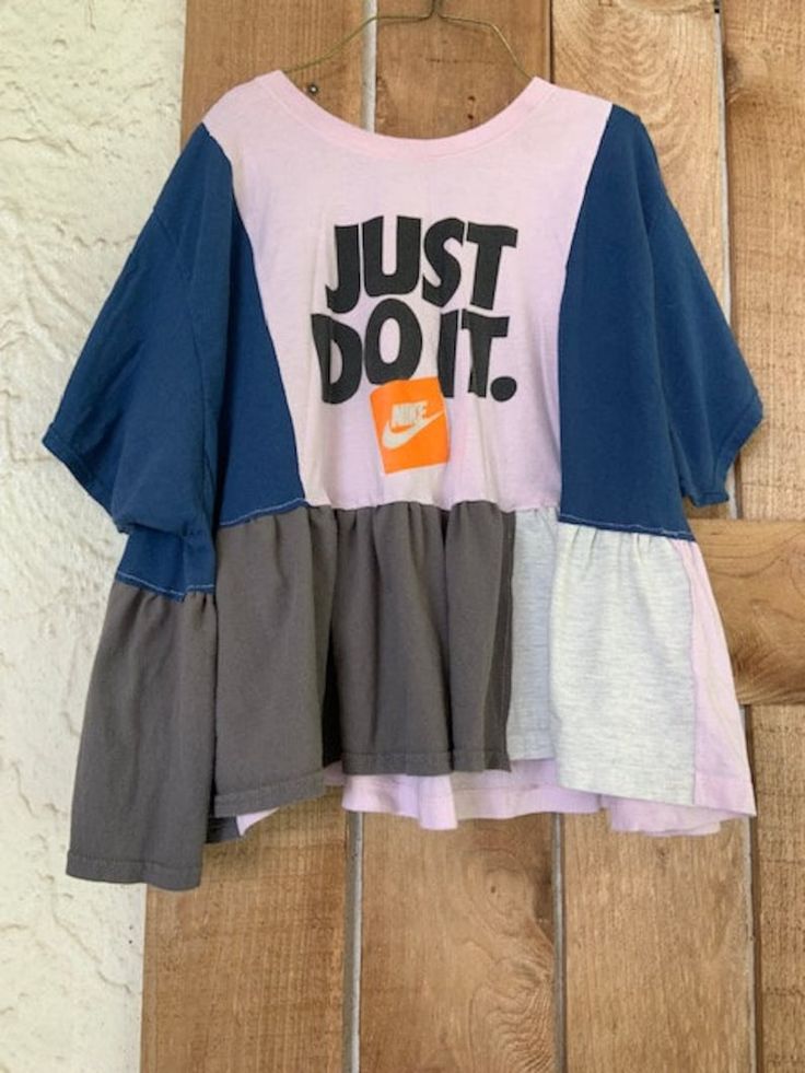 a t - shirt with the words just do it on it hanging from a wooden wall