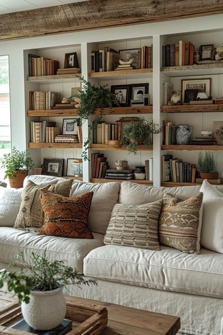 a living room filled with lots of white furniture and bookshelves on the wall