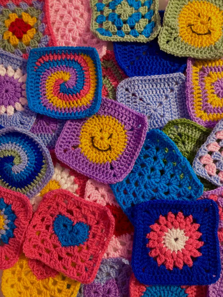 colorful crocheted squares with smiley faces are arranged on the floor in an array