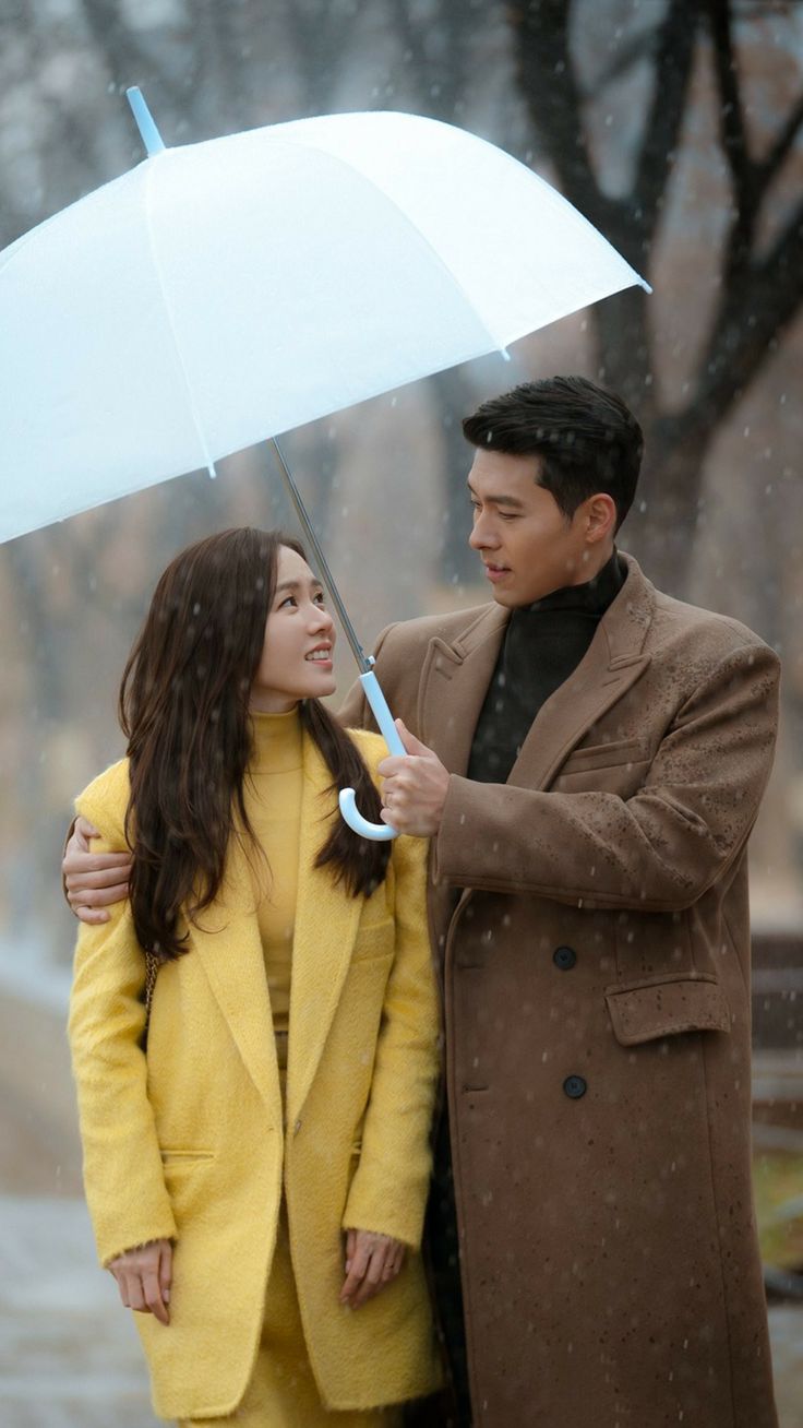 a man and woman standing under an umbrella in the rain