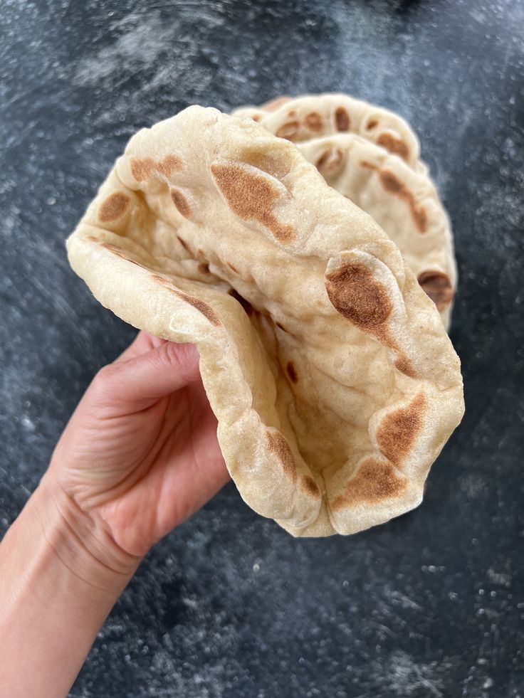 two flat breads being held up in the air by a person's hand