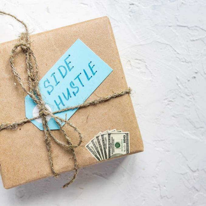 a package wrapped in brown paper and tied with twine, sitting on top of a pile of money