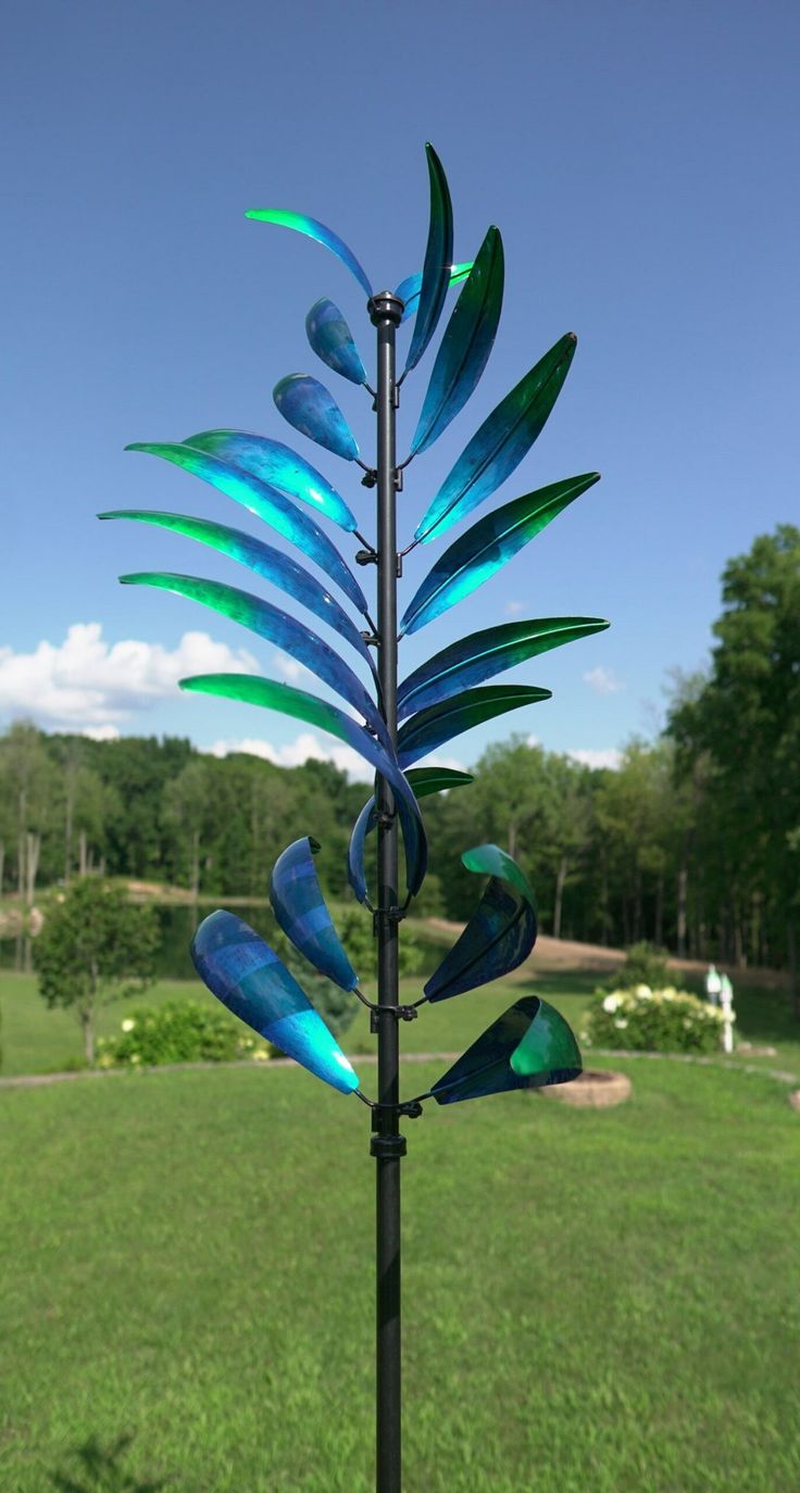 a blue glass sculpture on top of a metal pole in the middle of a field