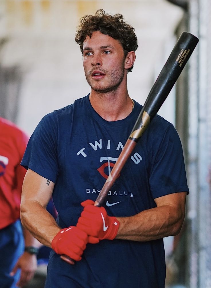 a man holding a baseball bat in his hands and wearing red gloves on the other hand