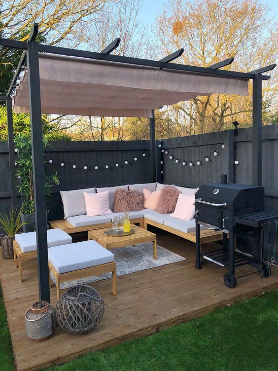 an outdoor living area with couches, table and bbq in the back yard