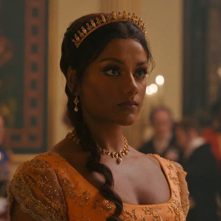 a woman in an orange dress wearing a tiara and looking off to the side