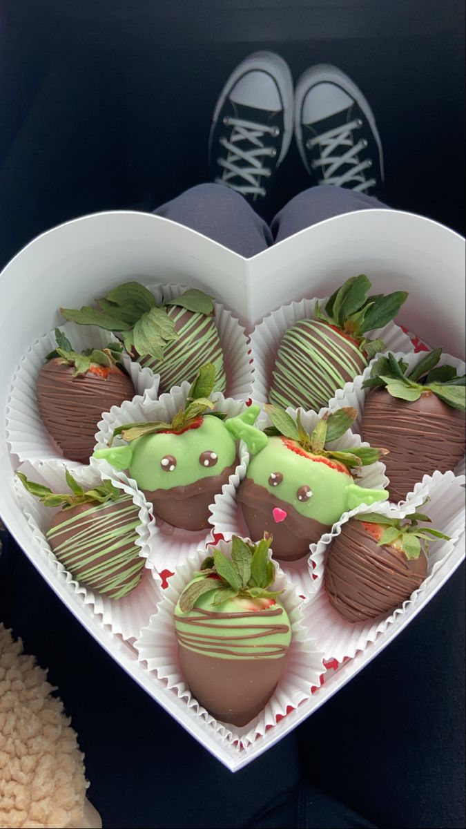 a heart shaped box filled with chocolate covered strawberries and topped with green frosting