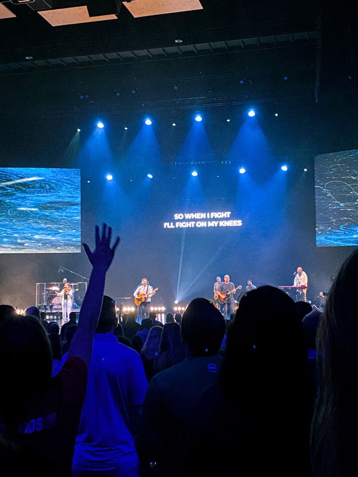 a group of people standing on top of a stage with their hands in the air