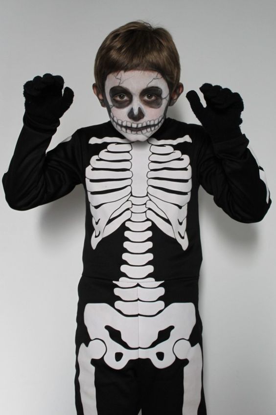 a young boy wearing a skeleton costume with his hands in the air and one eye closed