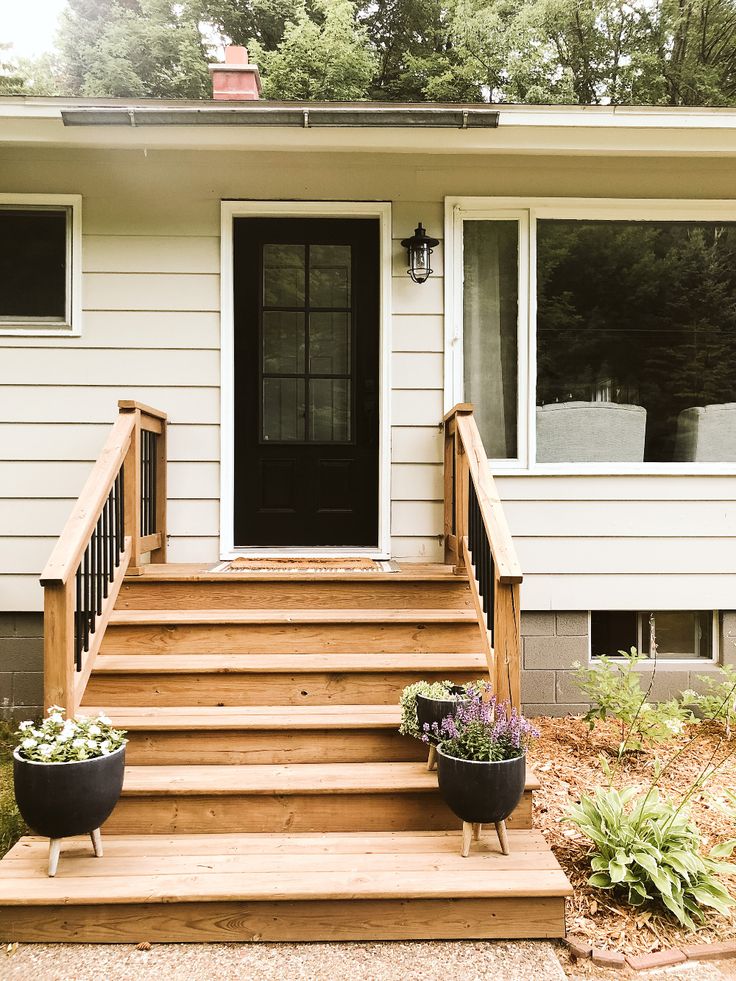 two planters are sitting on the front steps of a house that is painted white