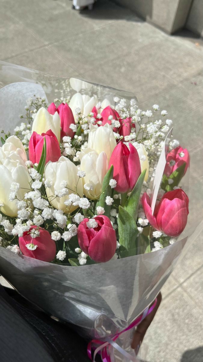 a bouquet of tulips and baby's breath sits on the back of a motorcycle