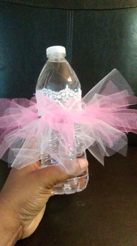 a hand holding a plastic bottle with pink tulle around it and a white cap on the top