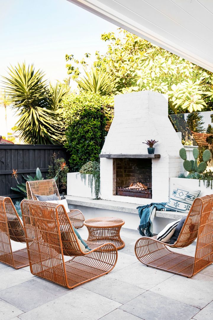 an outdoor fireplace with wicker chairs around it