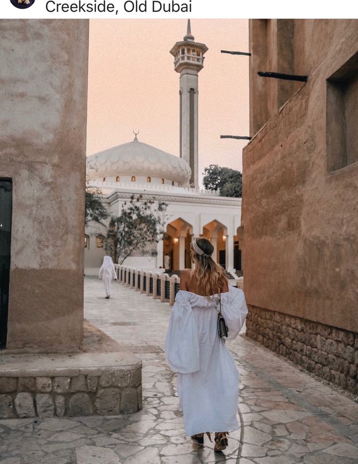 a woman standing in front of a building with a white dome on it's roof