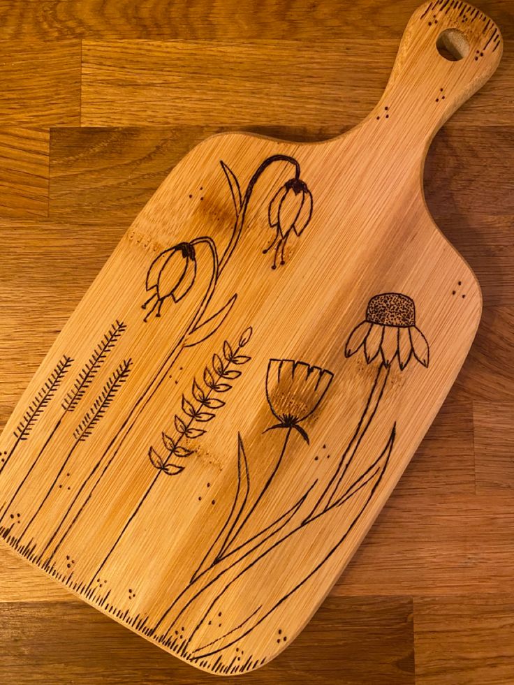 a wooden cutting board with flowers drawn on it