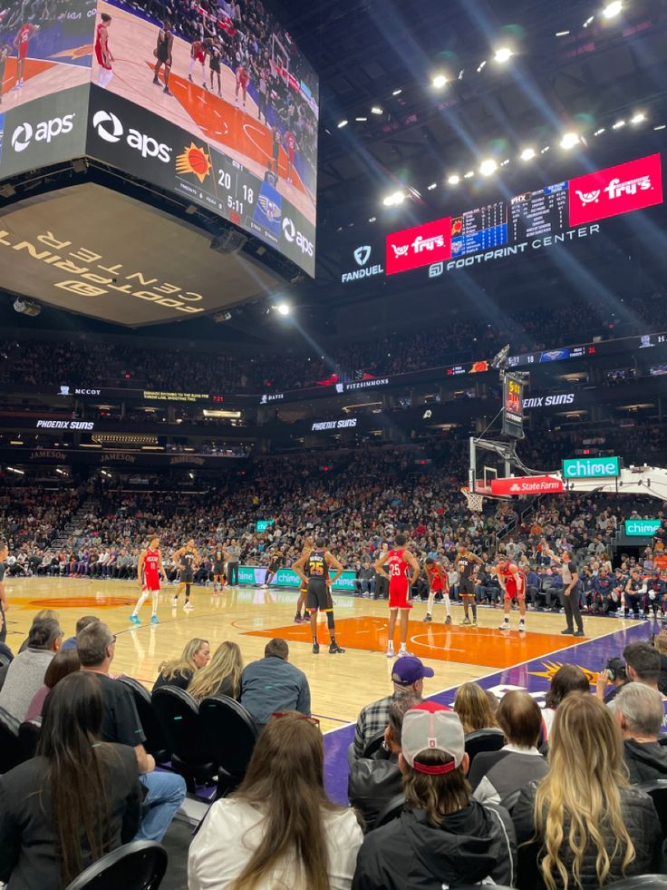 a basketball game is being played in an arena with people sitting on the sidelines